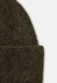 Brun strikket uld-beanie med en tekstureret overflade; har en rullet manchet og et blødt, fuzzy udseende.