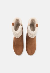 Botas de cano baixo em camurça castanha com um punho de pele sintética creme, fecho lateral por zipper, bico arredondado e textura suave. Sem detalhes de hardware visíveis.