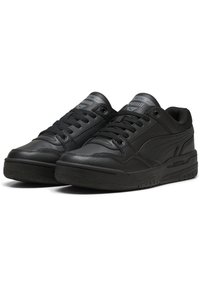Zapatillas negras de cuero con acabado texturizado, punta redondeada, suela plana y diseño de cordones. Presenta un sutil logotipo en la lengüeta y en el lateral.