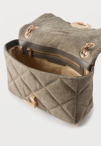 Ανοιχτή τσάντα χειρός από μπεζ καπιτονέ ύφασμα με χρυσές αλυσίδες-λώσεις, χρυσό κούμπωμα και εσωτερική επένδυση σε μπεζ χρώμα με τσεπάκι με φερμουάρ.