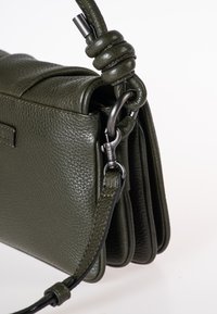 Borsa a mano in pelle verde oliva con finitura texture. Presenta un manico annodato, una tracolla removibile e dettagli in metallo argentato.
