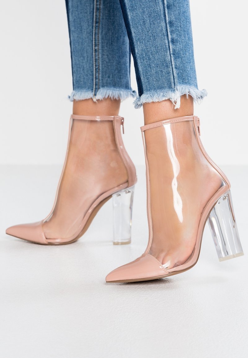 Bottes aux chevilles nues avec une tige transparente et un bout pointu, dotées d'un talon bloc clair et d'une fermeture éclair sur le côté, finition en patte vernie texturée.