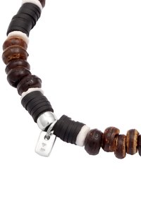 Perlenkette mit braunen Holzkugeln, schwarzen Gummidetails und einem silbernen Verschluss mit einem kleinen Etikett. Strukturierte und unterschiedlich geformte Elemente.