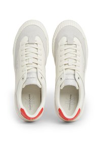 Białe sneakersy z gładką cholewką ze skóry i zamszu, okrągłym noskiem, sznurowadłami i czerwonym akcentem na pięcie. Teksturowana gumowa podeszwa.