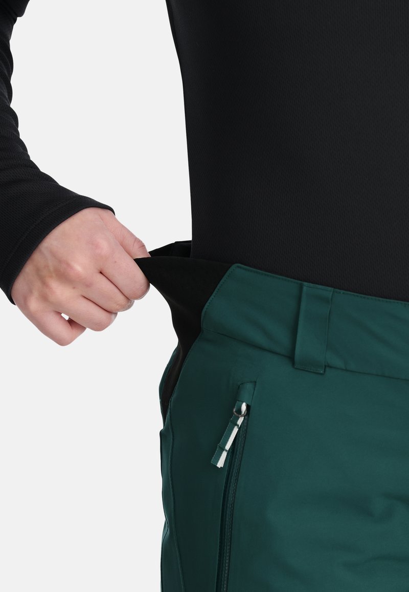 Wasserabweisende dunkle grüne Hose mit einer Reißverschlusstasche, elastischem Bund und weicher Innenausstattung; verstellbarer Bund.