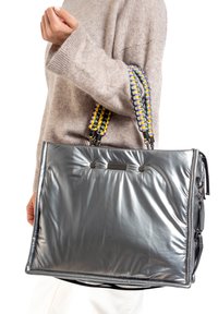 Sac fourre-tout gris rembourré avec une surface texturée, featuring des poignées tressées en jaune et violet, et deux accents de bouton noir à l'avant.