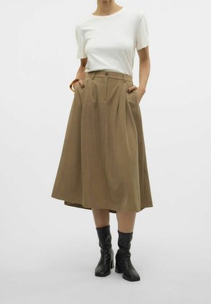 Brązowa spódnica midi z zakładkami, z wysokim stanem, dwie boczne kieszenie, zestawiona z białym t-shirtem z okrągłym dekoltem i czarnymi botkami na obcasie.