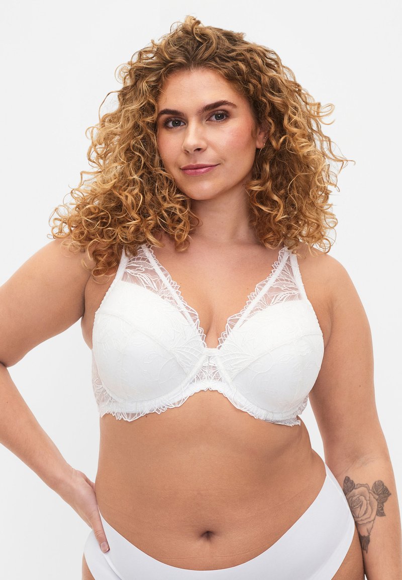 Witte kant bh met gevormde cups, bloemenborduursels en doorschijnende kantpanelen. Voorzien van verstelbare bandjes en een haak-en-oogsluiting.