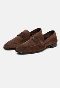 Brūni zamšādas loafers ar gludu tekstūru, kuros ir viena siksna pāri augšdaļai un zems kvadrātveida papēdis ērtībai.