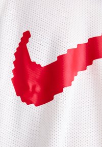 Hvid mesh trøje med et stort rødt pixeliseret Nike swoosh-logo. Materialet har små perforeringer, der forbedrer åndbarheden.