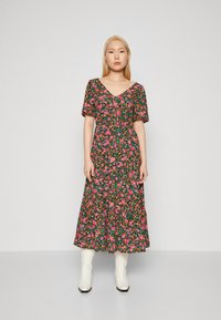 Robe à fleurs avec un fond noir et des fleurs colorées roses et vertes, décolleté en V, manches courtes et longueur midi fluide.