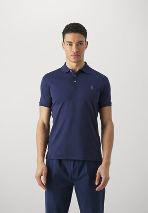 Polo majica kratkih rukava tamnoplave boje od pamuka, sa tri dugmeta na prednjem dijelu i malim izvezenim logom na grudima.