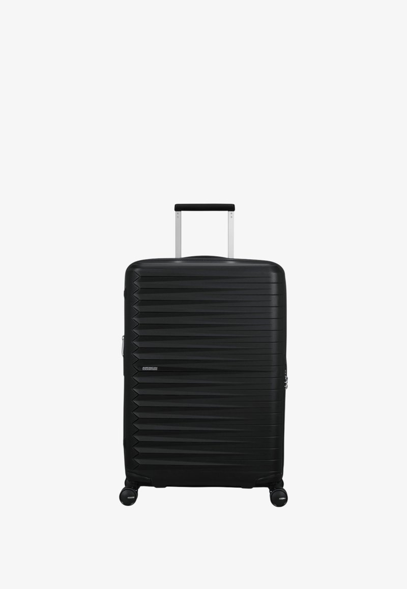 Maleta rígida negra con un diseño texturizado y estriado. Cuenta con un asa telescópica y cuatro ruedas para facilitar el desplazamiento.