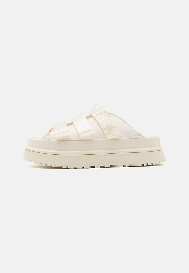 Beige slidesandalen met drie verstelbare banden, een dikke tussenzool en een rubberen zool met profiel; gladde textuur met een minimalistisch ontwerp.