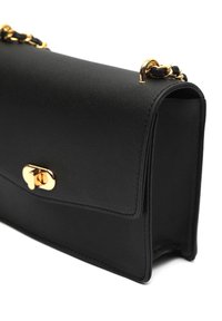 Borsa a mano in pelle nera con una texture liscia, hardware dorato e chiusura a pattina. Presenta una tracolla a catena e bordi curvi.