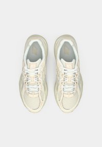 Sneaker in rete leggero con una combinazione di colori crema e rosa chiaro, caratterizzati da una suola ammortizzata, lacci e un logo ben visibile.