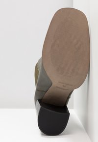 Oliwkowe botki za kostkę z gładkiej skóry, o kwadratowym czubku i słupku. Posiadają teksturowaną gumową podeszwę oraz wytłoczony logotyp marki.