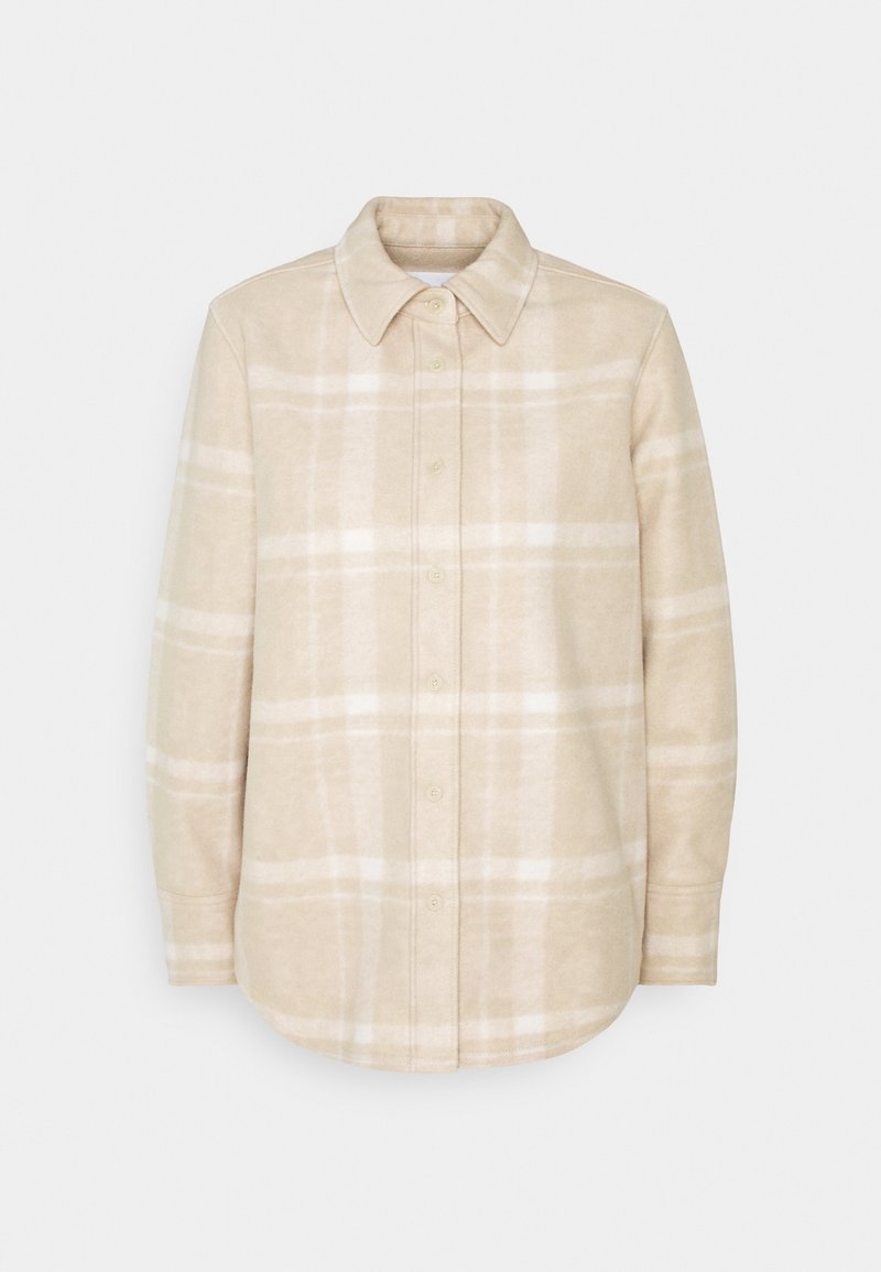 Chemise boutonnée à manches longues, beige et blanche à carreaux, avec col et patte de boutonnage à hauteur de poitrine, présentée sur fond blanc.