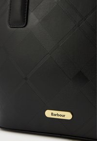 Geantă texturată neagră cu un model în diamant și o placă de accent aurie "Barbour". Material neted cu o formă structurată.