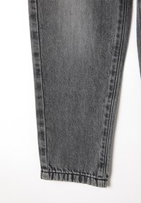 Pantalones vaqueros de mezclilla gris claro con un diseño ajustado, costuras visibles y un dobladillo limpio. La tela presenta una textura sutil y un ligero efecto de lavado.