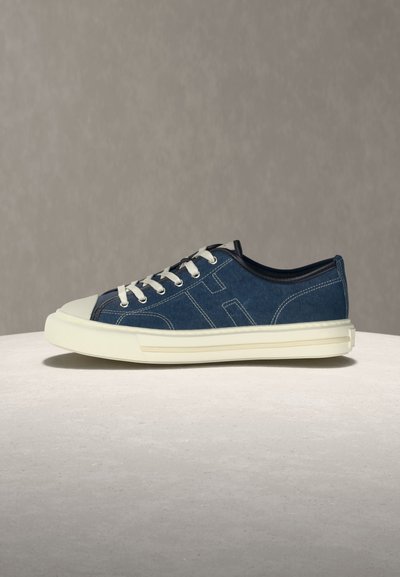 Χαμηλό τζιν αθλητικό παπούτσι με λευκή λαστιχένια σόλα, λευκά κορδόνια και μεγάλο ραμμένο "OH" στο πλάι, τοποθετημένο σε ανοιχτή επιφάνεια.