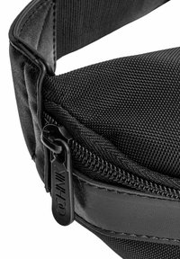 Czarna torba na pasku z teksturowanym wykończeniem, z gładkim zamkiem błyskawicznym i markową zawieszką. Kompaktowy design z regulowanym paskiem.