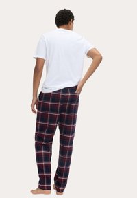 Herenpyjama's met een wit katoenen T-shirt en geruite flanellen broek in rood, marineblauw en wit, met een relaxte pasvorm en zijzakken.