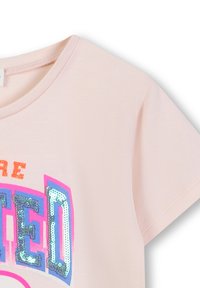 Lichtroze T-shirt met korte mouwen en een ronde halslijn, versierd met een multikleuren, sequined grafisch tekstontwerp in oranje, roze en blauw.