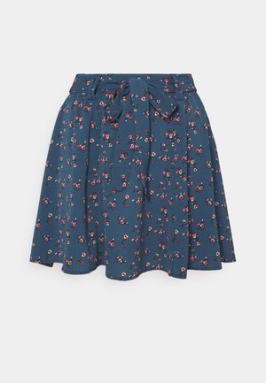Blå udvidet nederdel med lille rødt og hvidt blomsterprint, høj talje, bæltestropper og bundet stofbælte foran.