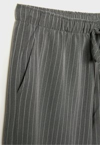 Pantalon gris avec fines rayures blanches verticales, taille élastique, poche latérale et un détail de lien en tissu sur le côté droit.