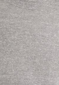 Grå stickad tröja med rund halsringning, med en jämn struktur och ett enhetligt mönster, gjord av mjukt, andningsbart tyg.