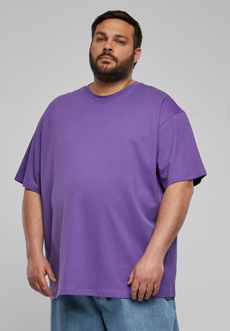 Tricou oversized de culoare mov, fabricat din bumbac, având guler tip crew și mâneci scurte. Textură netedă cu o croială lejeră.