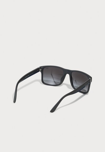 Schwarze Kunststoff-Sonnenbrille mit quadratischem Rahmen, gradienten grauen Gläsern und mattem Finish. Verfügt über ein Logo an den Schläfen und gebogene Bügel.