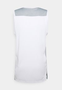 Top sin mangas de tela blanca con un panel gris claro en los hombros. Presenta aberturas laterales para mayor libertad de movimiento y una textura suave.