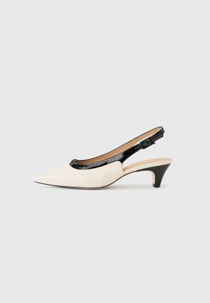 Chaussure slingback crème à bout pointu avec petit talon kitten noir, garniture noire brillante et bride ajustable.