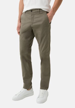 Olivenfarvede bomulds-chinos med lige snit, der har knaplukning, sidelommer og er parret med hvide sneakers.