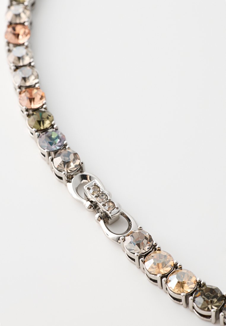 Zilverkleurige armband met ronde, meerkleurige strassstenen en een toggle-sluiting, met een gladde afwerking en afwisselende tinten.