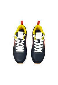 Zwarte leren sneakers met witte veters, gele voering, rode accenten en een geperforeerd ontwerp. Voorzien van een klein trekbandje op de hiel.