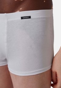 Boxer da uomo bianchi in cotone con una texture liscia e cintura elastica, contraddistinti da un piccolo etichetta nera "SKINY" sul retro.