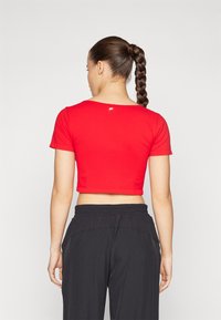 Rød kortermet t-skjorte med avrundet hals og en liten logo på ryggen. Kombinert med svarte bukser med elastisk midje.