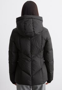 Giacca a vento nera con cappuccio, presenta un design trapuntato, finitura testurizzata e maniche lunghe. Progettata per calore e copertura.