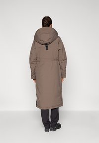 Long brown parka jacket with a large hood, cinched waist, and side slits. Features a matte texture and black accent hardware.
