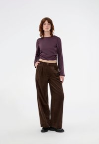 Long-sleeve purple satin top paired with brown corduroy wide-leg pants, featuring a button closure and subtle vertical texture. Black shoes.