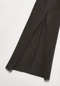 Black fabric trousers with a smooth texture, featuring a side zipper and drawstring detail. The legs have a slight flare.