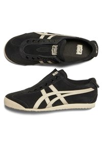 Černé semišové tenisky s krémovými detaily, s klasickým šněrováním, zaoblenou špičkou a texturovanou podrážkou pro lepší přilnavost.