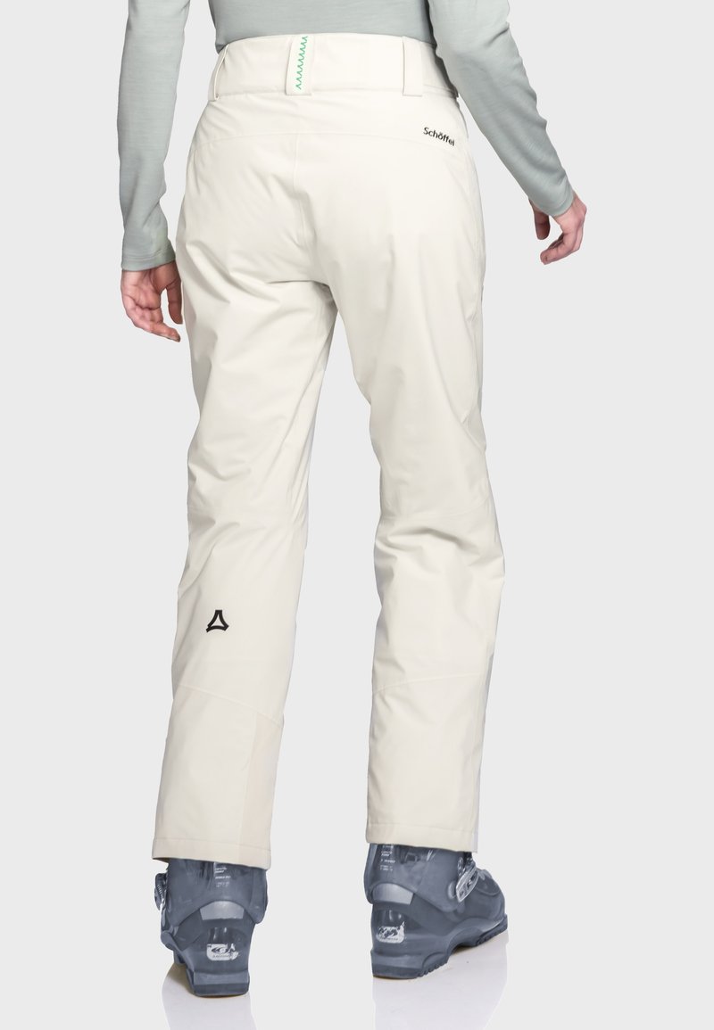 Beige Skihosen aus wasserabweisendem Material, mit hohem Taillenbund, Reißverschluss-Taschen hinten und Logodetail nahe dem Knöchel.