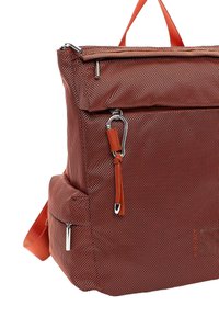 Rød tekstureret rygsæk med en vandret lynlås øverst, sidelomme med lynlås og orange læderdetalje. Har en robust strop og reflekterende hardware.