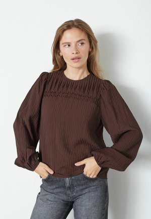 Blusa marrone, strutturata, con design a coste e maniche a sbuffo. Caratterizzata da un collo rotondo e dettagli plissettati sul petto.