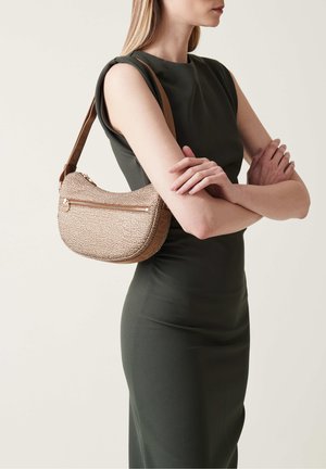 Borsa a spalla in materiale strutturato oro e marrone, forma curva, con una tasca frontale con zip e una singola tracolla regolabile.