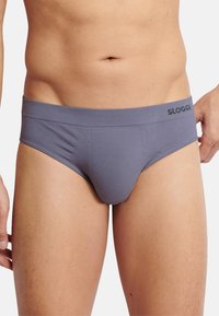Grå briefs lavet af blødt stof med en glat tekstur, der har en bred elastik med brandnavnet "SLOGGI" prægede.